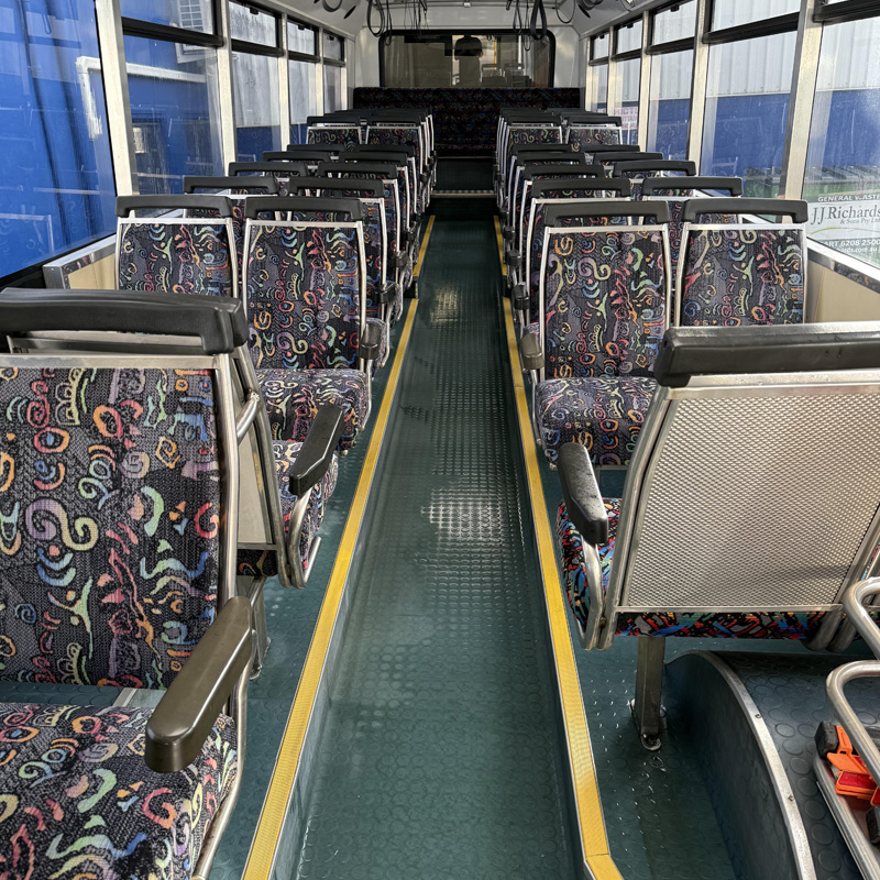 Bus interior with rows of patterned fabric seats and a green aisle