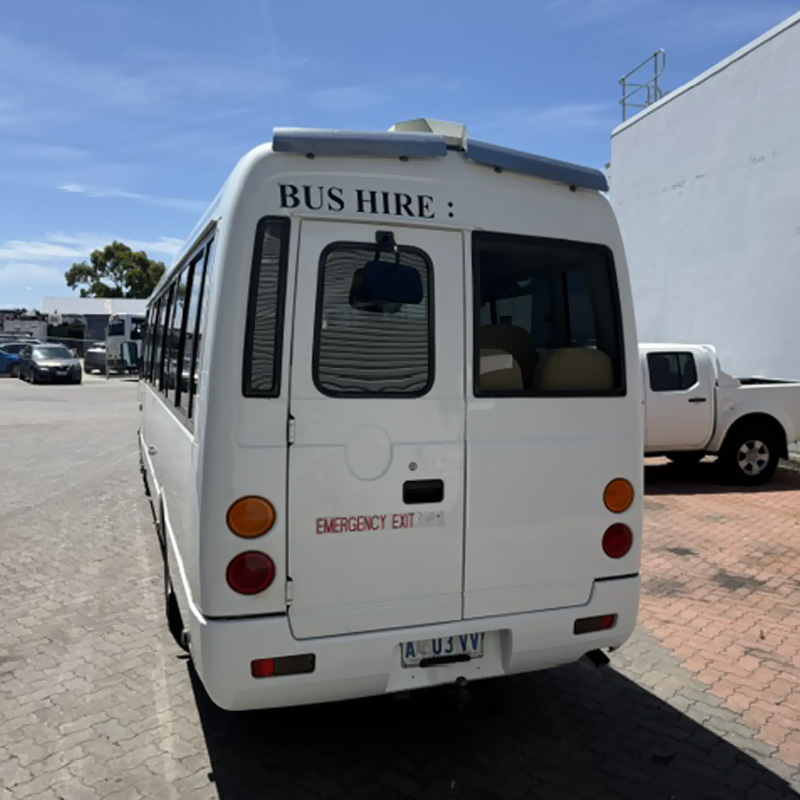 Rear of a white minibus with Bus Hire lettering and an emergency exit door