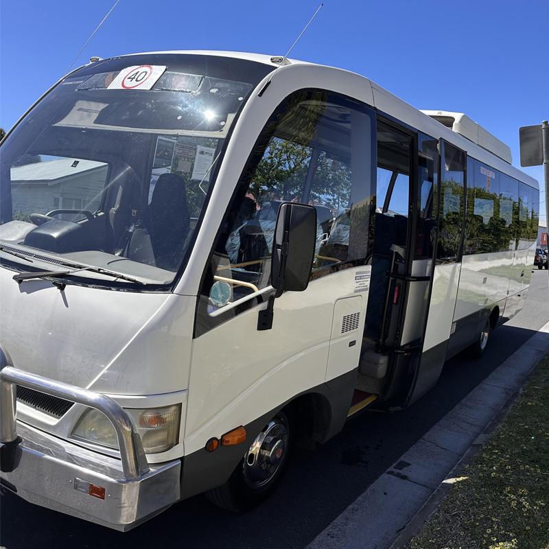 White minibus with a bull bar and its front door open, parked at the kerb