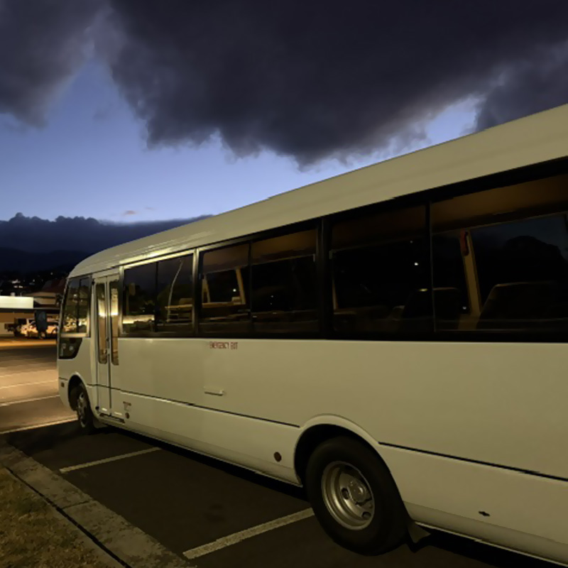Cream coach parked in a car park at dusk under dark storm clouds