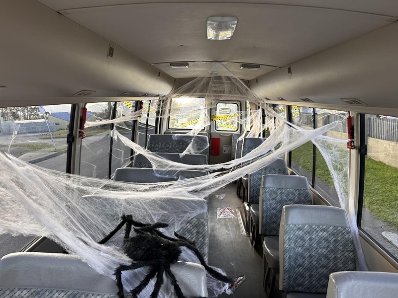 Bus interior decorated with fake cobwebs and a giant toy spider across the seats