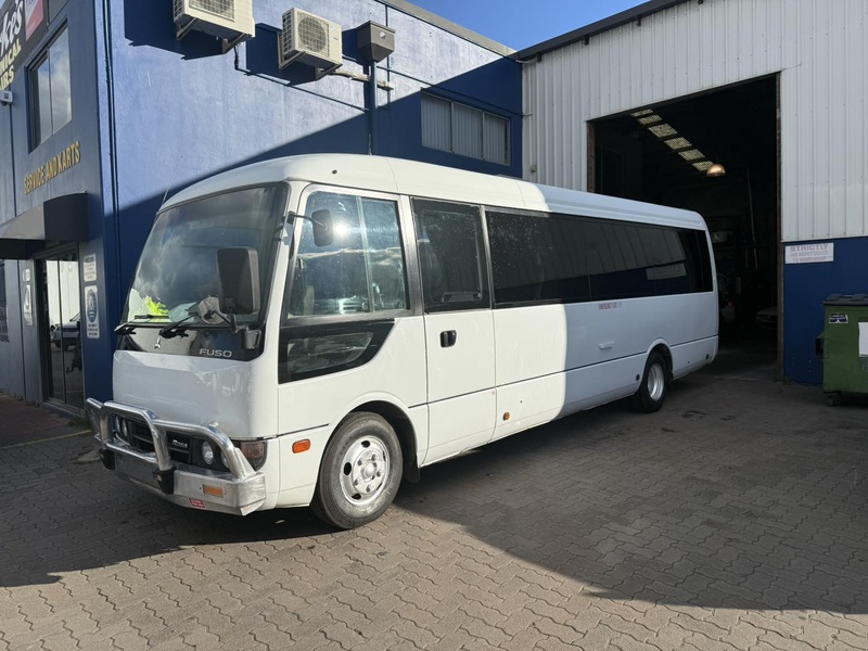 White minibus with a bull bar parked outside a blue workshop's open roller door