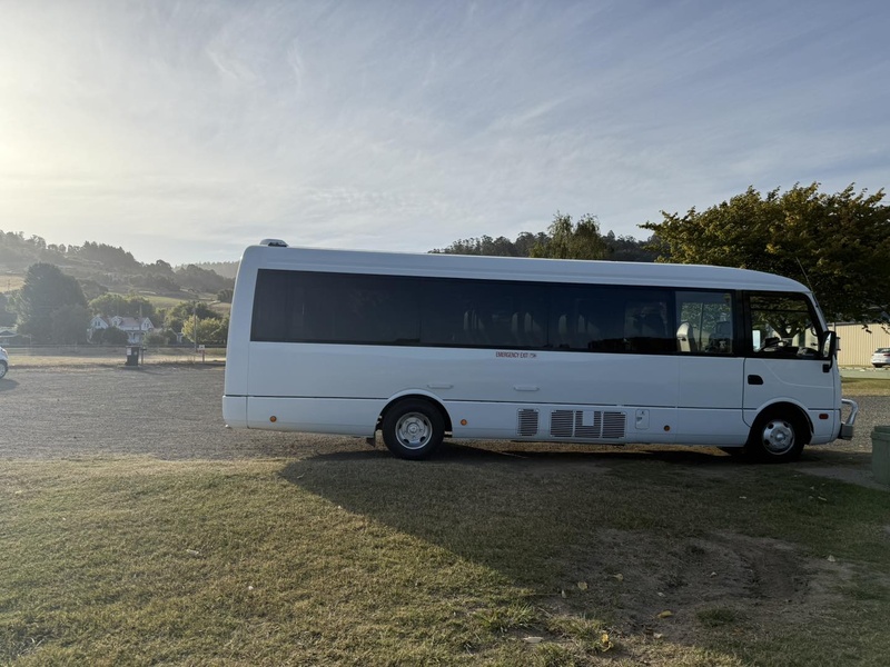 White minibus parked side-on on a grassy field in late-afternoon sun