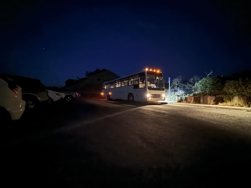 Coach with its lights on, parked on a dark road at night