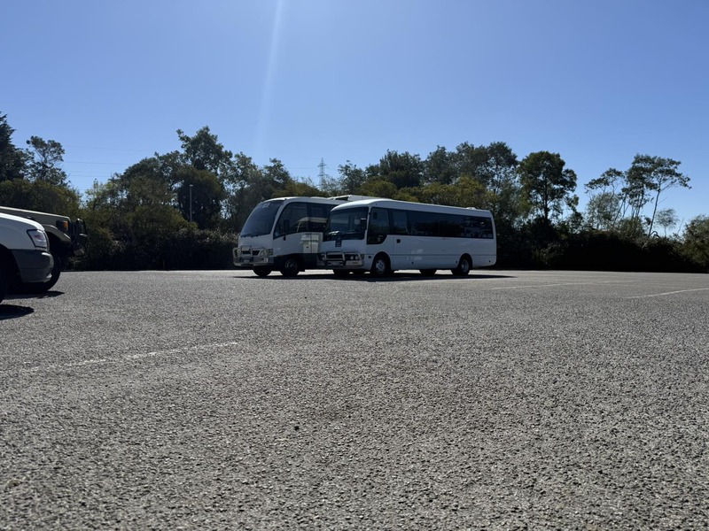Two white buses parked at the far side of a large empty car park