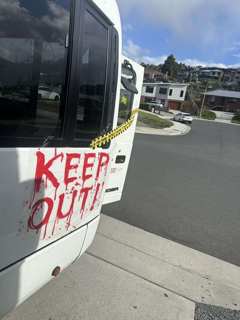 Side of a bus with Keep Out! written in fake blood and caution tape, a Halloween decoration