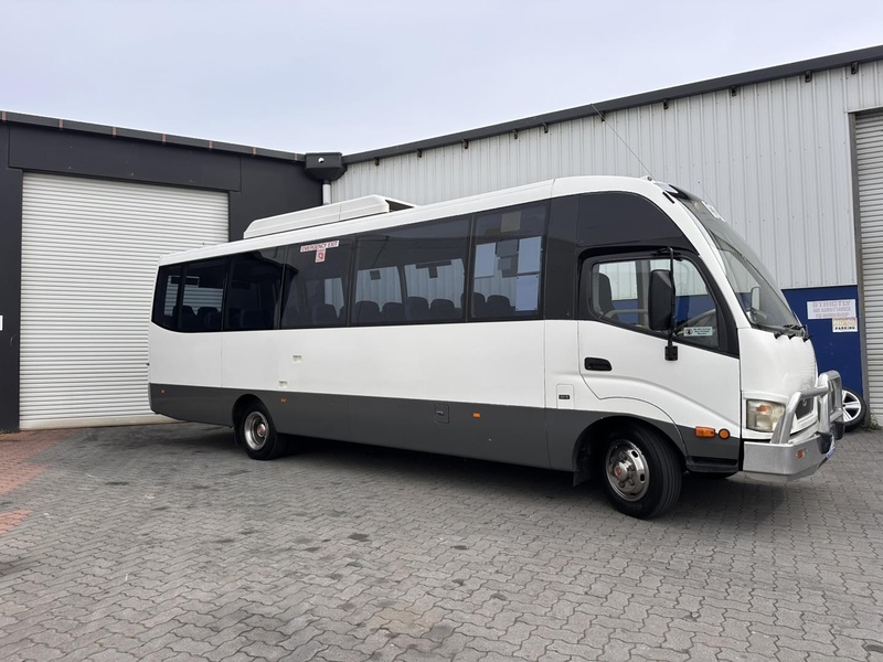 White midi bus with a bull bar beside a grey shed's roller door
