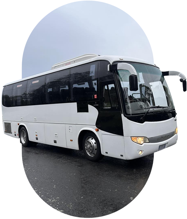 White coach with its headlights on, parked on a wet road, in an oval frame