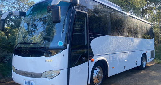 Higer Midi Coach parked on a dirt track among bush